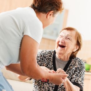 Personal håller äldre leende kvinnas händer